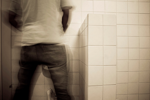 man urinating in bathroom urinal