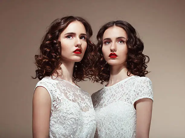 Studio portrait of two beautiful twins. Professional make-up and hairstyle. High-end retouch.