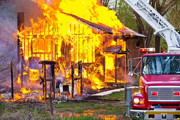 Burning House Fire with Fire Truck.  House engulfed with flames showing framing of house totally on fire.  Orange blaze reflecting in water.  Captured as a 14-bit Raw file. Edited in ProPhoto RGB color space.