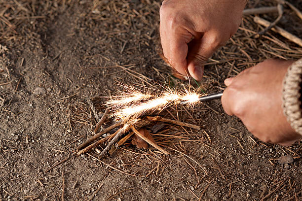 Man starting fire with ember and twigs Starting fire with Swedish fire steel. Survival, bushcraft skill. cigarette lighter stock pictures, royalty-free photos & images