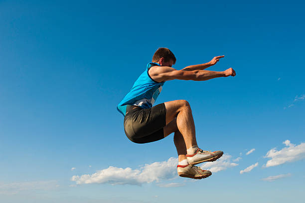 Young male athlete at long jump Side view of young male athlete at long jump against the blue sky long jump stock pictures, royalty-free photos & images