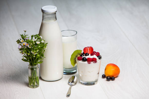 glass of yogurt with raspberry, black currants, strawberrie and kiwi on wooden background