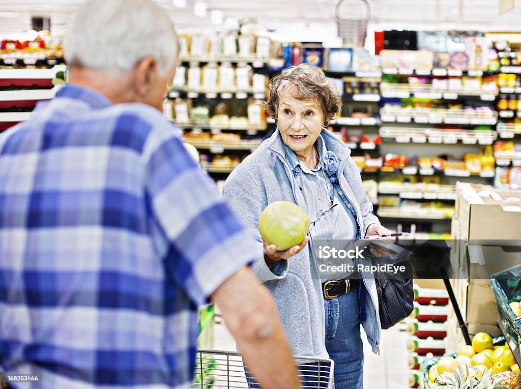 Mujer mayor consulta marido de toronja en supermercado compras - Foto de stock de Supermercado libre de derechos