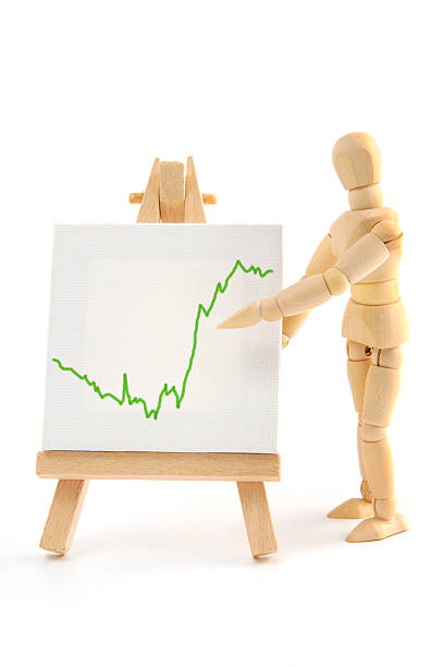Wooden mannequin pointing with hand on business graph
