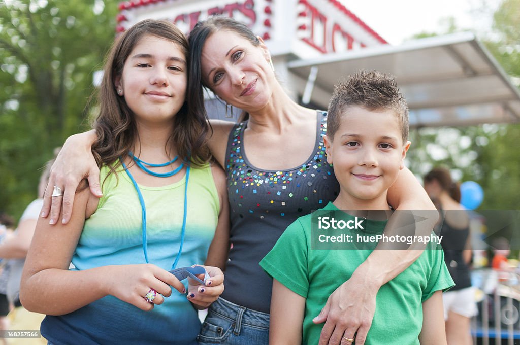 Family at a Festival Woman and her two children buying tickets for rides at a carnival. Family Stock Photo