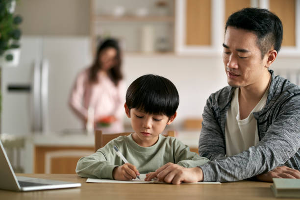 young asian father helping son with homework stock photo