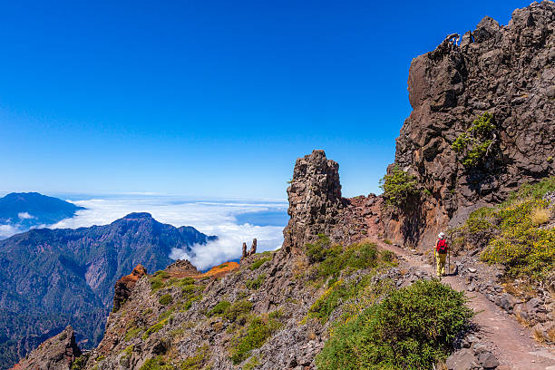 Footpath in the Caldera de Taburiente National Park, La Palma Woman walking on the footpath No. E7, from Pico de la Nieve to Roque de los Muchachos, in the Caldera de Taburiente National Park. This beautiful park is a ring of summits of 8 km in diameter with peaks reaching to 2000 meters, crossed by numerous well-marked trails. Canary Islands, Spain la palma canary islands photos stock pictures, royalty-free photos & images