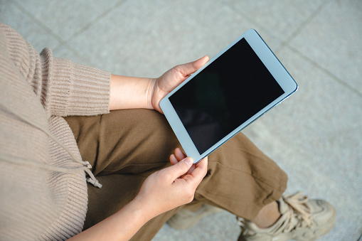 A woman sitting on a park bench using a tablet