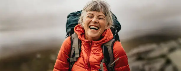 Vibrant senior woman embraces an active lifestyle during her retirement, embarking on a scenic hike and enjoying life to the fullest. Demonstrating healthy aging and longevity. This elderly hiker's passion for adventure showcases the importance of regular exercise and embracing nature for overall health and wellness, proving that aging gracefully is attainable through determination and a love for the great outdoors.