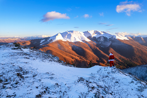 Rear view of Santa Claus admiring the snow capped mountains at sunset, Apennines, Latium, Italy, Europe