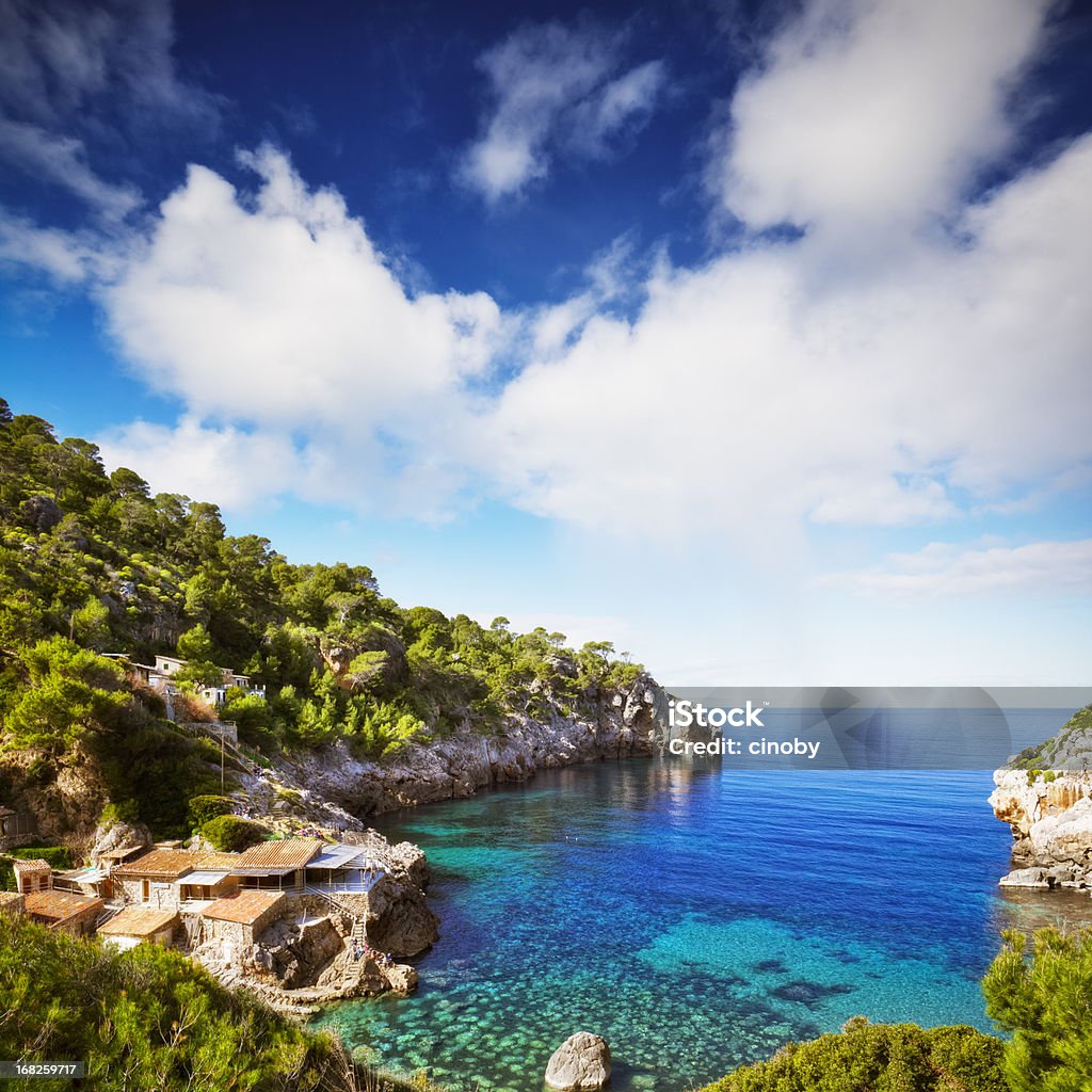 Deia Creek - Majorca Below the village of Deia is the small pebble Cala Deia with developed to boat garages natural caves. Cala Deia is located between Punta de Son Beltran and Sat Pedrissa. This beautiful, surrounded by medium-high cliffs bay is covered with garrigue and Aleppo pines and ends in a semi-circular beach, a mountain stream flows and where rising terraces. Coarse sand and gravel form the heavenly, heavily sloping beach. On the sides there is a small jetty, Escars and some restaurants. In the summer you can see here and internationally known personalities. Majorca Stock Photo