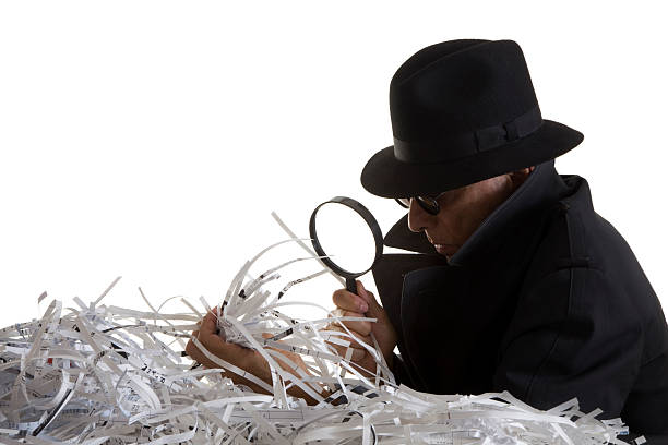 Indentity Thief sifts through shredded documents stock photo
