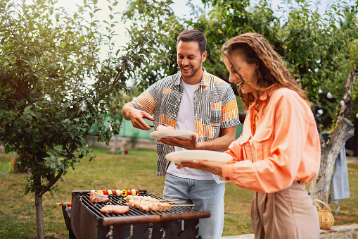 Young Caucasian couple, wife and husband, making barbecue