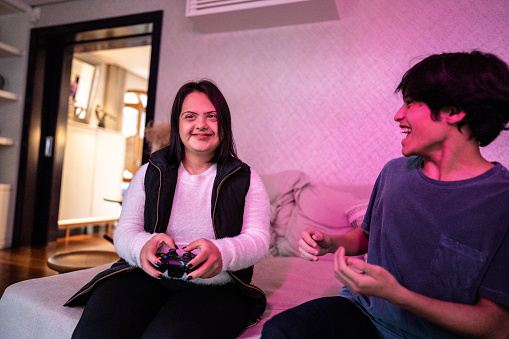 Happy siblings playing video game at home - including woman with down syndrome