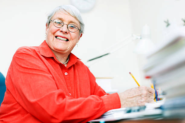 istock Still busy at 70, smiling woman works in office 168260404