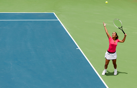 A young girl hitting a very powerful tennis serve.