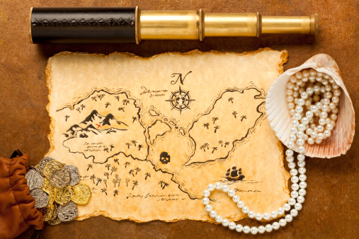 Open treasure chest on sand full of golden coins, gems and pearls, 3d rendering