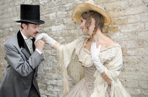Young English man kissing this beautiful girls hand. Victorian style coarting.