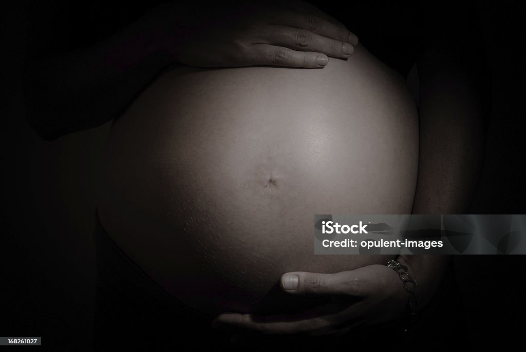 Pregnant Mother Pregnant mother cradling her stomach. Dark moody image with a number of concept uses. Naked Stock Photo