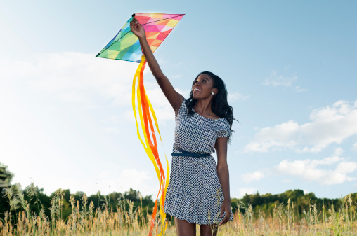 Young woman flying a kite in a meadow.