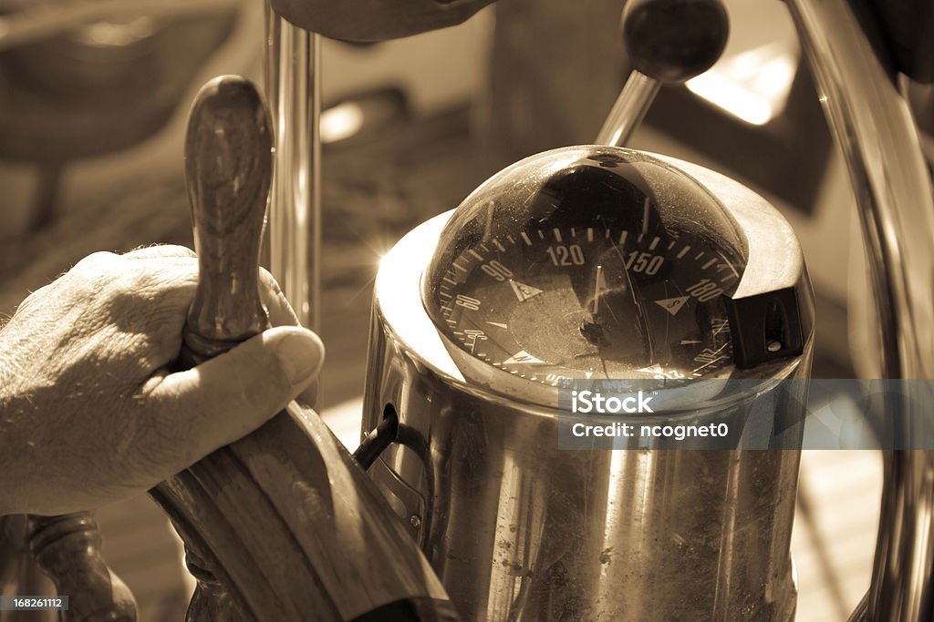 Driving a Yacht sepia shot of mans hand on a steering wheel Helm - Nautical Vessel Part Stock Photo