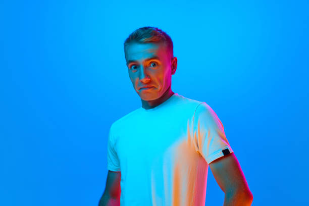 istock Wow. Young man's portrait on blue studio background in neon light, filter. Handsome, attractive male surprised model in casual style. 1682617604