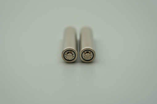 The head of an AAA 1.2V rechargeable battery with the outer casing removed, gray background