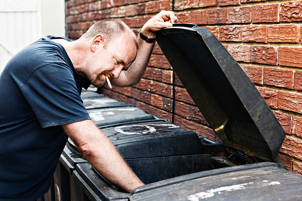 hombre investiga dumpster scruffy sin hogar - brick wall homelessness wall begging fotografías e imágenes de stock