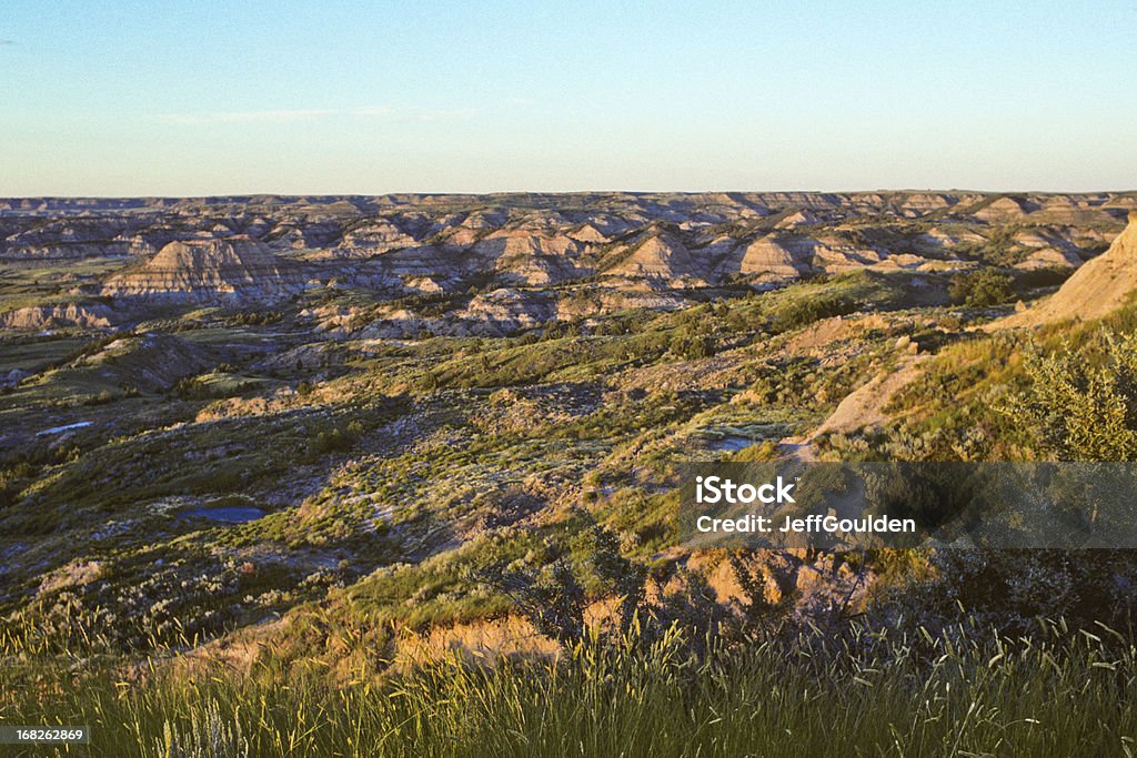 The Badlands at Sunset Theodore Roosevelt National Park lies where the Great Plains meet the rugged Badlands near Medora, North Dakota, USA. The park's 3 units, linked by the Little Missouri River is a habitat for bison, elk and prairie dogs. The park's namesake, President Teddy Roosevelt once lived in the Maltese Cross Cabin which is now part of the park. This picture of the badlands at sunset was taken from the Painted Canyon Overlook. North Dakota Stock Photo