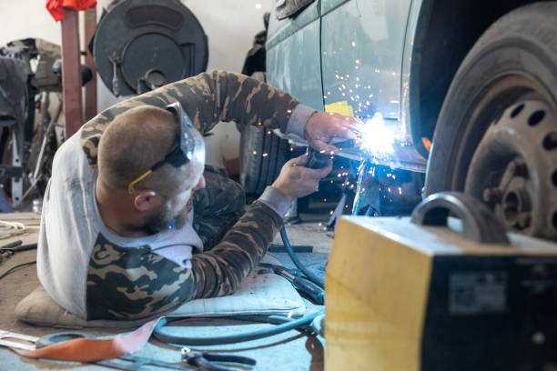 the professional auto mechanic uses a welding machine to repair a car. - car bodywork flash imagens e fotografias de stock