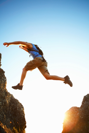 Man jumping from one rock to another while trekking