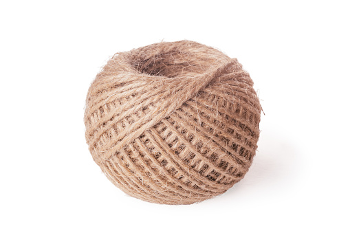 Close-up of coil ball of brown jute hemp natural rope twine on white background. Isolated. Textile, equipment, sewing, crocheting, handcraft, knitting, decoration, hobby, vintage, crafts, packaging.
