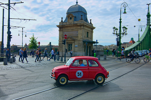 Budapest, Hungary-01 October, 2019:Iconic vintage red car Fiat 500 (side view) rides fast in the street of the Budapest, Hungary. Perfectly restored Fiat 500.