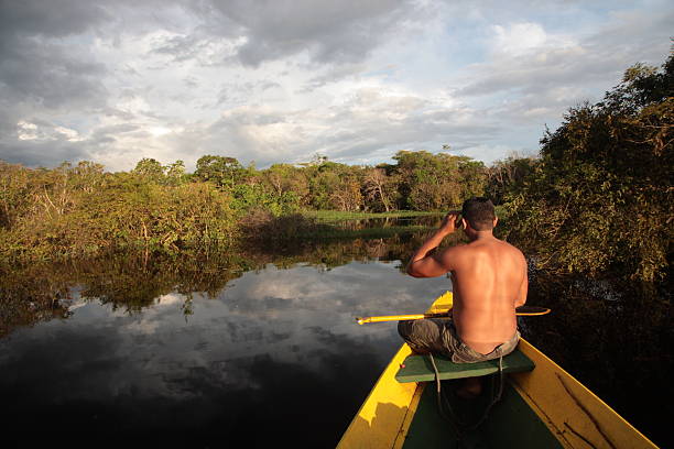 man sitting on boat in Amazon jungle river, Brazil stock photo