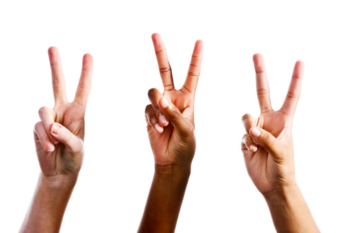 Three female hands all give the hand signal indicating Peace or Victory, isolated against white. 