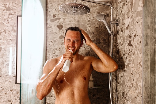 Beautiful man having fun while taking a shower