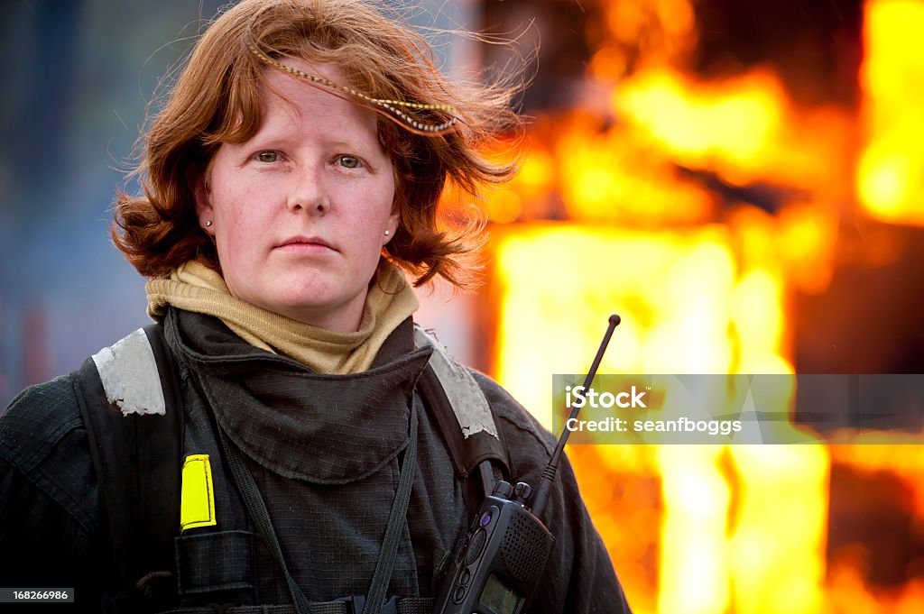 Female firefighter in front of structure fire Female firefighter in front of structure fire with copy-space Firefighter Stock Photo
