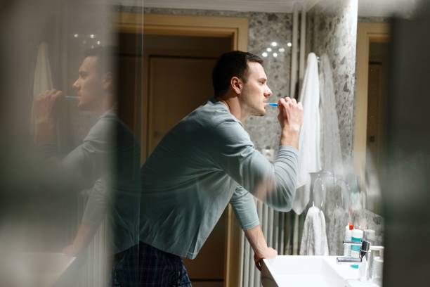 istock Beautiful man brushing his teeth in the bathroom 1682670717