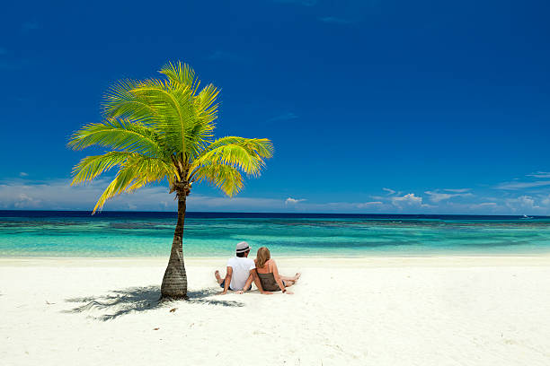 Couple sitting on tropical beach stock photo