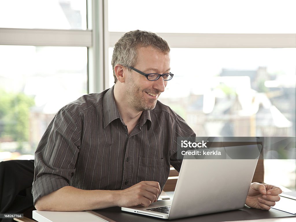 Homem de negócios madura sorrindo trabalhando no laptop - Foto de stock de 50-54 anos royalty-free