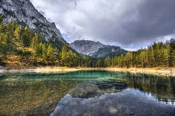 HDR of Green Lake in Styria Austria - Gruener See. European Alps. dark clouds reflection in the mountain lake.