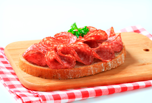 Slice of bread with salami on a cutting board