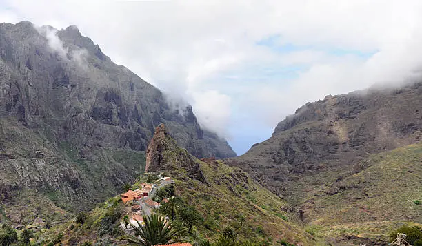 panorama image of small mountain village Masca in Tenerife (Spain) gets visited by hundred thousands of tourists every year. In background Masca typical rock. Masca is located in Buenavista del Norte in Teno Mountains. 