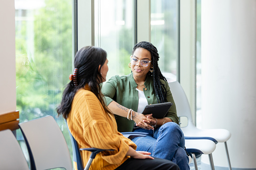 An unrecognizable young adult woman shares her problems with the young adult female counselor.