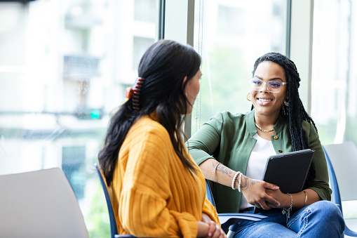 The young adult female guidance counselor listens carefully to the young adult female student.