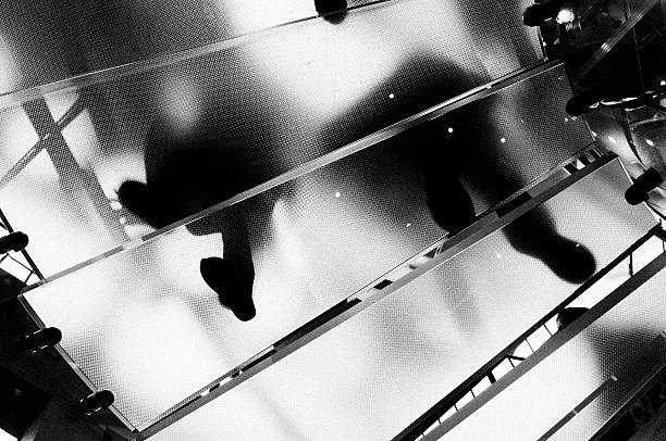 People Moving Up Glass Staircase.NYC.Black And White. People on Staircase high contrast stock pictures, royalty-free photos & images