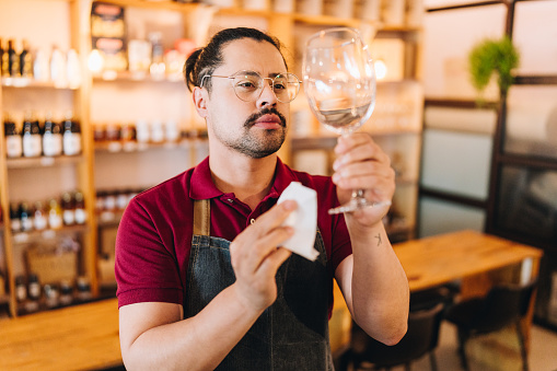 Waiter cleaning a wine glass with a cloth