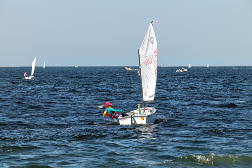 Group of men enjoying sailing on a summer day on calm sea. They are relaxing on mild sun at autumn