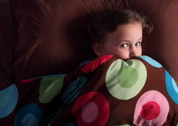 Little girl in her bed, looking very frightened