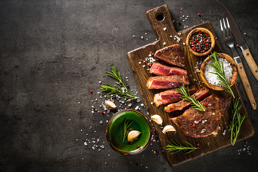 Beef steak. Grilled meat at wooden cutting board. Top view image with copy space.
